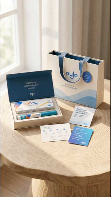 Unboxing do kit Aylo sobre mesa de madeira à luz da janela: caixa azul-marinho aberta com medicamento, sacola off-white com hangtag azul e cartões de boas-vindas
